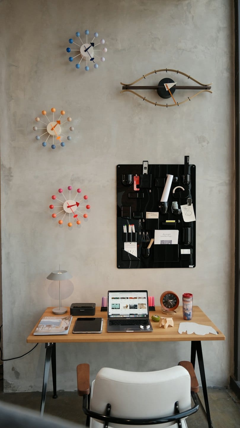 Modern home office with laptop and wall clocks.